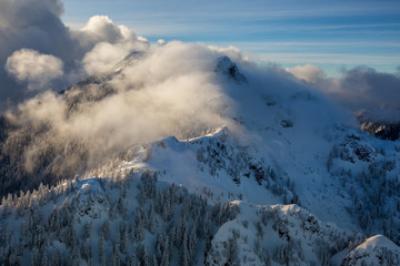 Aerial landscape view of the coastal mountains north of Vancouver, British Columbia, Canada, during a cloudy winter evening.