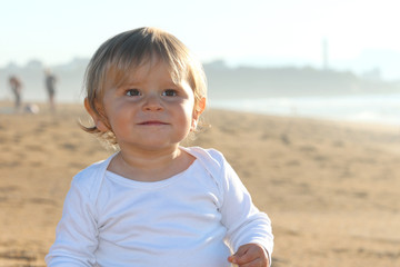 Happy blond baby playing at the beach