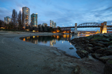 View on the sandy beach in Vancouver Downtown, BC, Canada, with False Creek, Burrard Bridge and buildings in the background.