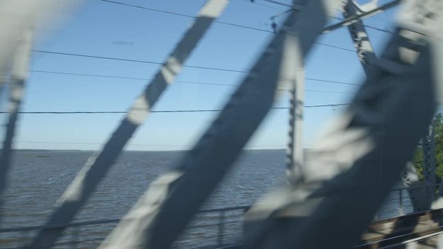 POV: High-speed Train moves on a bridge past a lake in a sunny day