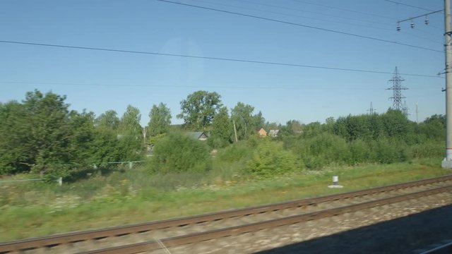 POV: High-speed Train moves past a village and a station in the summer