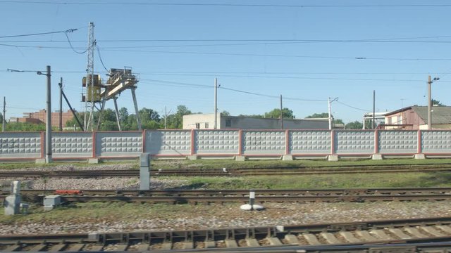 POV: High-speed Train moves past a railway station in the summer