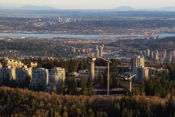 Aerial City view of Burnaby Mountain and Simon Fraser University  (SFU), with City of Surrey in the background. Picture taken in British Columbia, Canada, during a cloudy evening.