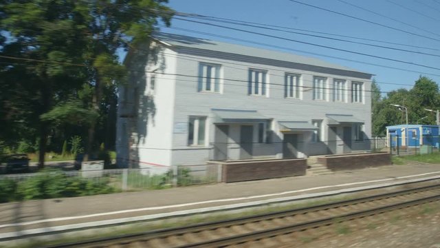 POV: High-speed Train fast moves past a railway station in a town in the summer