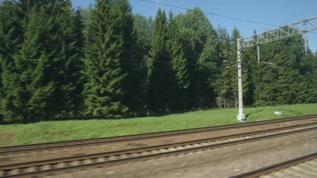 POV: High-speed Train fast moves past a forest and a railway in the summer