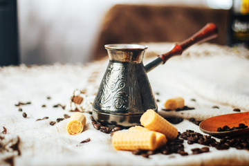 Coffee background. Vintage copper turkish coffee pot, cezve or ibrik, roasted coffee beans on blue wooden background. near round wafers