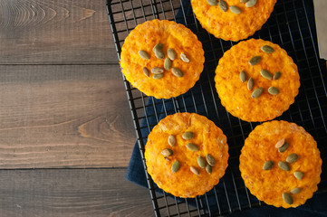 Pumpkin scones on a wire rack over wooden background.