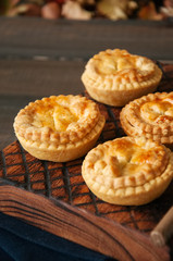 Mini meat pies from flaky dough on a wooden board over wooden background.