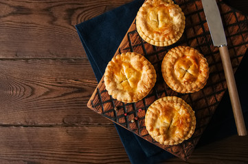 Mini meat pies from flaky dough on a wooden board over wooden background. - 174662704