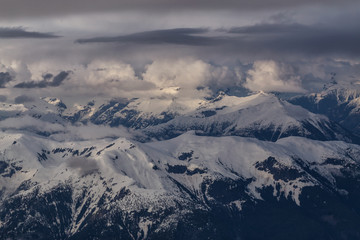 Fototapeta premium Aerial landscape view of beautiful mountain range with cloud layers during sunset. Taken in a remote area North of Sunshine Coast, British Columbia, Canada.