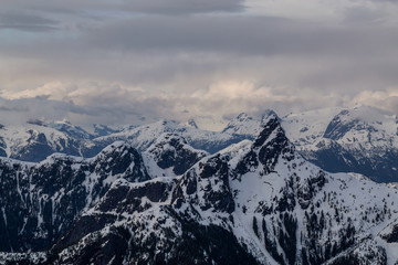 Aerial landscape view of beautiful mountain range with cloud layers during sunset. Taken in a remote area North of Sunshine Coast, British Columbia, Canada.
