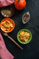 Pumpkin creamy mac and cheese baked pasta over black stone background. Comfort food.
