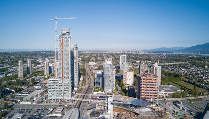 Naklejka premium Widok z lotu ptaka na duży plac budowy w centrum handlowym z kolejką miejską i budynkami mieszkalnymi w pobliżu. Zrobiono w Burnaby, Vancouver City, British Columbia, Kanada.