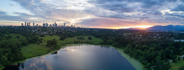 Aerial View of Deer Lake Park with Metrotown City Skyline in the backgournd. Taken in Burnaby, Greater Vancouver, British Columbia, Canada, during a cloudy sunset.