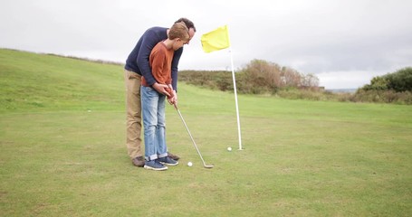 Father teaching son how to play golf