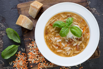 Above view of italian soup with lentil and pasta served in a white plate, studio shot
