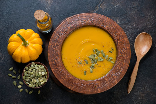 Pumpkin cream-soup with addition of pumpkin seeds and spices, view from above, studio shot