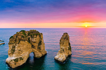 Beautiful sunset on Raouche, Pigeons' Rock. In Beirut, Lebanon.Sun and Stones are reflected in water.dense clouds in the sky. - obrazy, fototapety, plakaty
