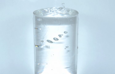 water dropping in drinking glass on white background