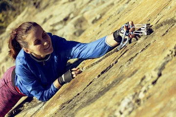 Foto op Aluminium woman rock climber climbs on the cliff. rock climber climbs on a rocky wall. woman makes hard move. top view © vetal1983