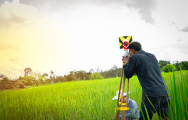 Asian smart engineer or surveyor in black jeans and long sleeve shirt are measuring the lands of...