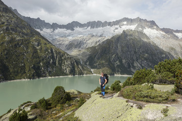 Fototapeta na wymiar Hiker enjoys the breathtaking view of a mountain lake in the Swiss Alps