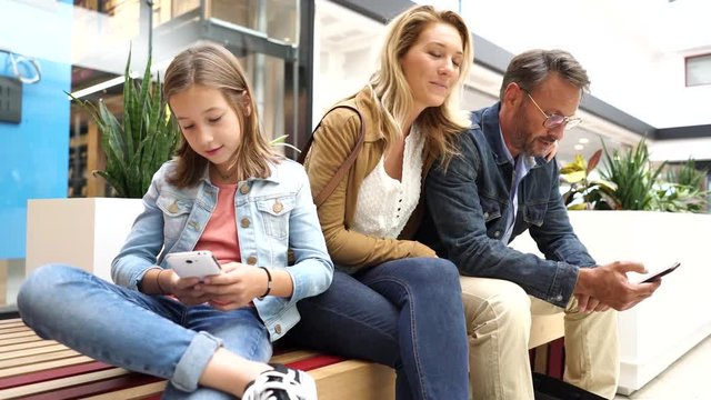 Family on shopping day in mall, sitting on public bench