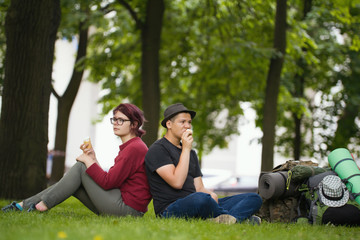 Young couple tourists with backpacks are eating the icecream in the park