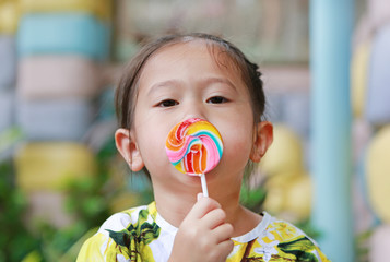 Adorable girl licking lollipop.