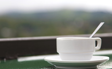 Hot Coffee cup on the wooden table and the plantations background