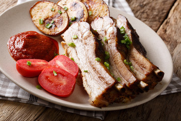 Delicious roast pork brisket with potato skins, tomatoes and sauce on a plate close up. horizontal