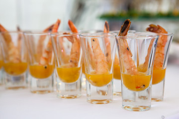 individual Cocktail Shrimp shot glasses with delicious homemade tartar spicy sauce for Christmas dinner or cocktail party, bokeh background, close-up, selective focus
