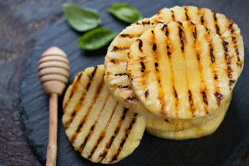 Close-up of grilled sliced pineapple topped with honey, selective focus, horizontal shot