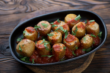 Baked potatoes cooked in sicilian style and served in a metal plate, selective focus