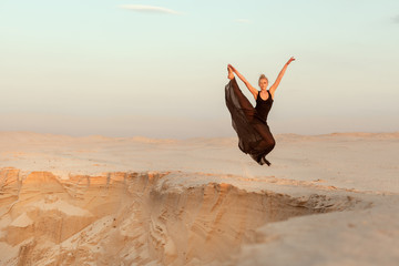 Woman in dance flies over an abyss in the desert. © Petro