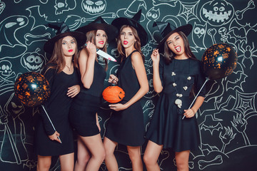 Beautiful girls in witches costumes on a dark background with a picture. Halloween.