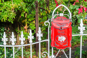 Red vintage mailbox hanging on the gate.