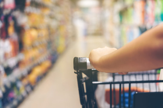 Asian woman's hand with supermarket, trolley and many objects that are blurred background.This image is blurred and Soft focus.