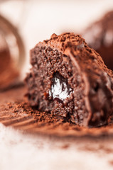 Chocolate chip muffin in brown wax paper. Unwrapped. Cocoa powder in the background