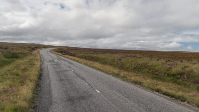 POV shot from a camera attached to the front of a vehicle driving through beautiful empty roads in the scottish highlands