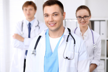 Fototapeta premium Cheerful smiling male doctor with medical staff at the hospital