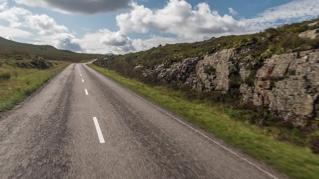 POV shot from a camera attached to the front of a vehicle driving through beautiful empty roads in the scottish highlands