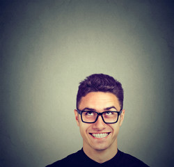 Handsome happy young man in glasses looking up