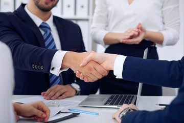 Business handshake at meeting or negotiation in the office, close-up. Partners are satisfied because signing contract or financial papers