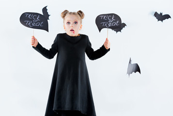 Little girl witch in black dress over magical accessories. Halloween, the studio evening.