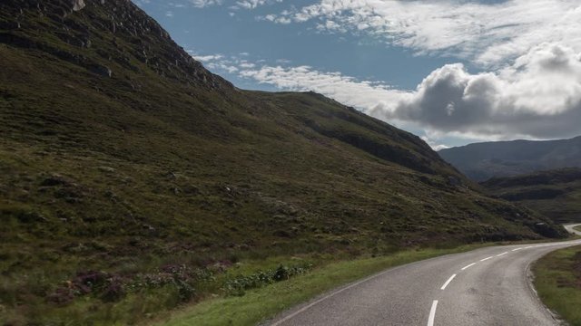 POV shot from a camera attached to the front of a vehicle driving through beautiful empty roads in the scottish highlands