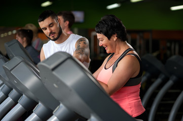 Fototapeta na wymiar Fitness coach assisting his client on treadmill