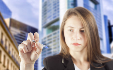 Obraz premium business woman with pen writing and office building blurred in background. focus on the hand