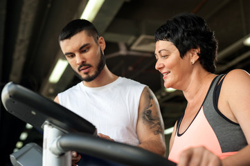 Middle aged woman with personal coach in gym