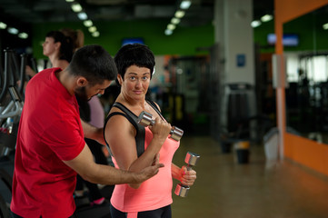 Brunette woman doing weight exercise with coach